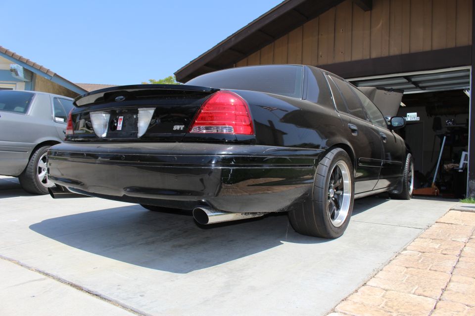 Rear quarter of a black sedan with SVT badge and single exhaust in a driveway