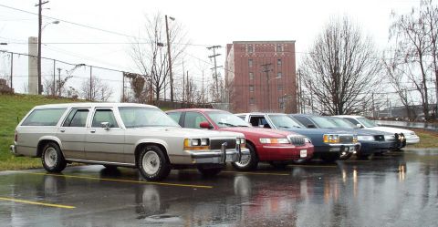 1998 Ford Crown Victoria - Multiple vehicles lined up in a parking lot on a cloudy day.