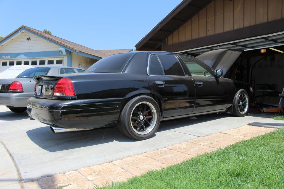 Rear quarter of a black sedan in a driveway with a second sedan behind it