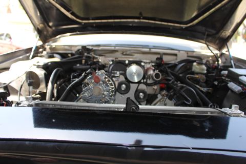 2003 Ford Crown Victoria - Engine bay seen across a glossy black cowl, revealing a polished front pulley assembly and master cylinder.