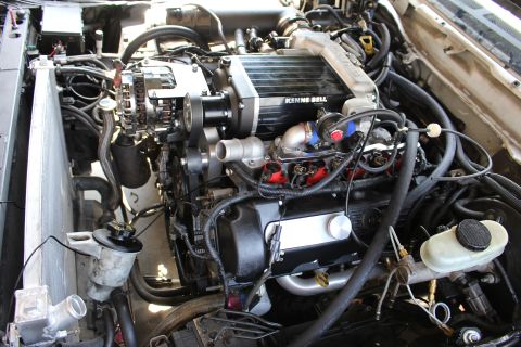 2003 Ford Crown Victoria - Close engine-bay view of a black Kenne Bell supercharger mounted over a V8, with alternator and reservoir caps visible.