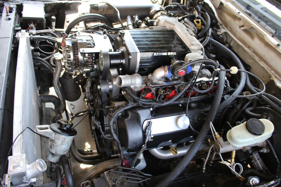 Engine bay close-up of a Kenne Bell supercharger over a black V8 with alternator