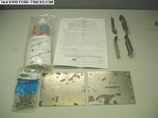 Ford repair kit with adhesive tubes, instructions, metal brackets, rivets, and two sheet metal panels on a table