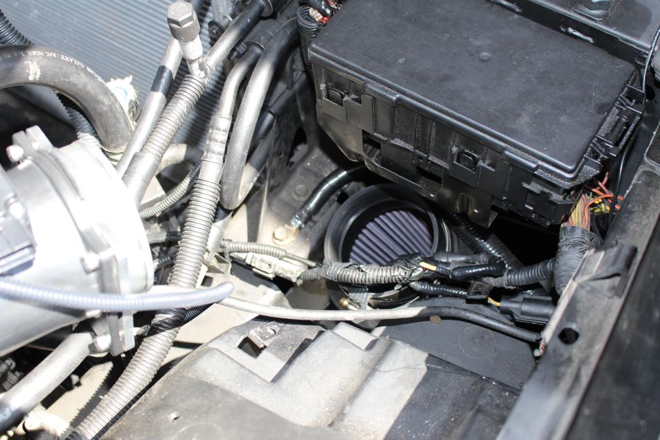 Cone air filter beside black fuse box and wiring harness