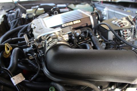 2003 Ford Crown Victoria - Kenne Bell supercharger mounted above a large black intake tube, with hoses and a chrome accessory at right.