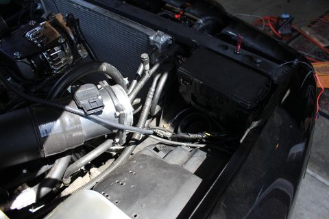 2003 Ford Crown Victoria - engine bay view showing an intake tube, black fuse box, wiring and the radiator support panel.