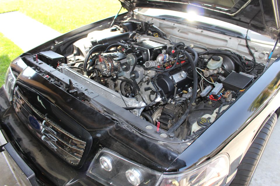 Engine bay of a black Ford car with hood up, radiator support removed