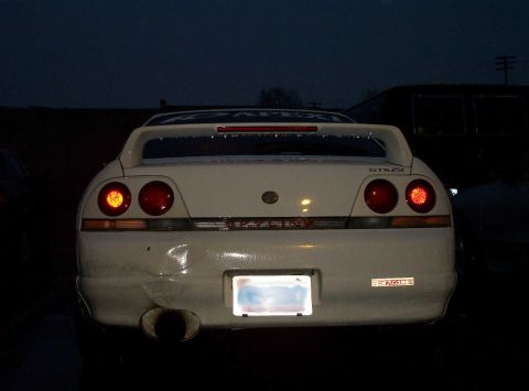 1998 Ford Crown Victoria - Rear view of a white Nissan Skyline GT-R with its taillights illuminated, parked outdoors at night.