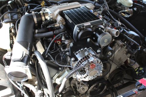 2003 Ford Crown Victoria - Wide engine bay shot showing a Kenne Bell supercharger, intercooler, polished alternator and tangled wiring.