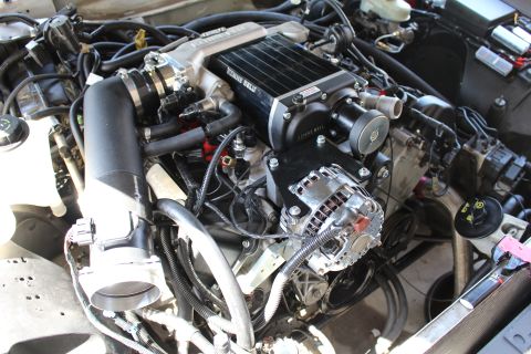 2003 Ford Crown Victoria - Engine compartment showing a black supercharger, polished alternator and black intake tubing across the bay.