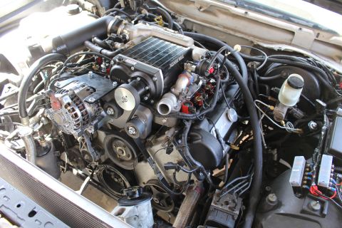 2003 Ford Crown Victoria - Engine bay view showing a supercharger with intercooler core, polished alternator and brake master cylinder reservoir.