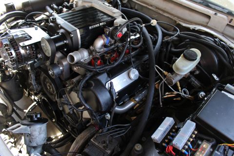 2003 Ford Crown Victoria - Side angle of an engine bay with a Kenne Bell supercharger, valve cover, brake reservoir and an exposed fuse box.