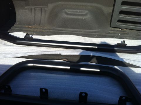 1982 Ford Bronco - Two black side steps are placed in the bed of a pickup truck, ready for installation.