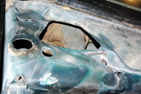 1995 Ford Bronco - This image shows the underside of a damaged car hood, revealing rust and holes.