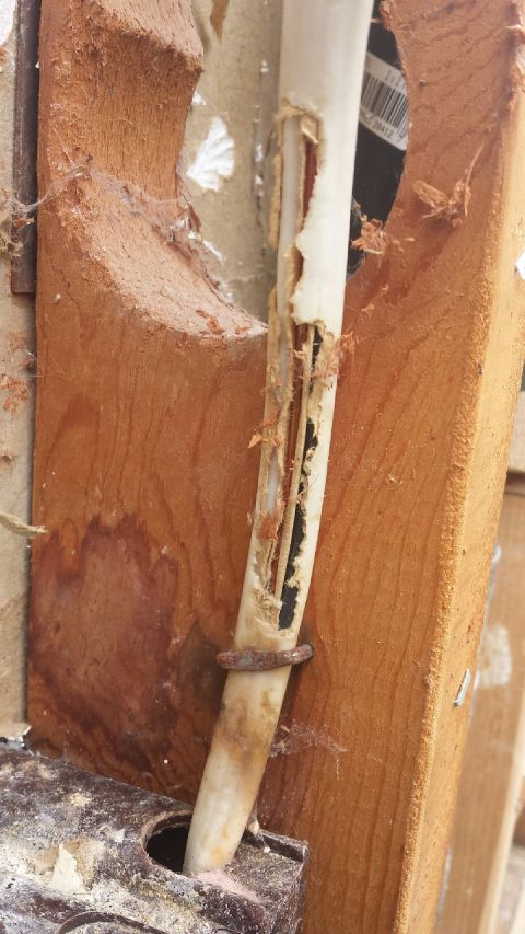 1989 Ford Bronco - Close-up of a damaged conduit with visible wiring and a rusty metal clamp.