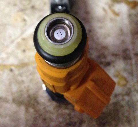 1989 Ford Bronco - A single fuel injector is shown in detail, highlighting its nozzle and orange casing.