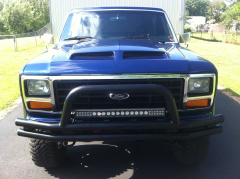 1982 Ford Bronco - Blue Ford Bronco with aftermarket hood scoop and front bumper modifications.