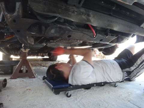 1993 Ford Taurus - A person works on the underside of a vehicle supported by jack stands.