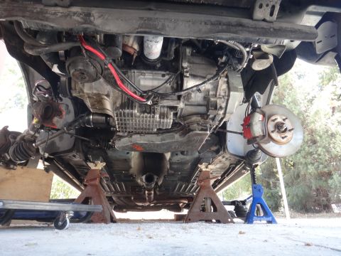 1993 Ford Taurus - The underside of a vehicle is visible, supported by jack stands, with focus on the drivetrain and suspension.
