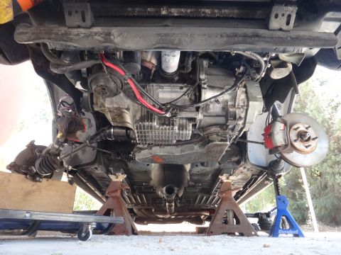 1993 Ford Taurus - The underside of a vehicle is visible, supported by jack stands, revealing its mechanical components.