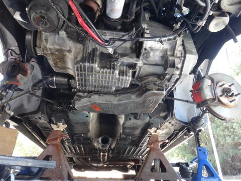 1993 Ford Taurus - Underside view of a vehicle's transmission and engine components, supported by jack stands, with brake and suspension parts visible.