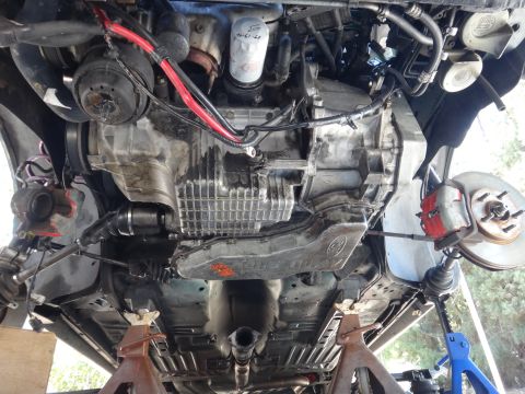 1993 Ford Taurus - The undercarriage of a vehicle is visible, supported by jack stands, with the engine and transmission exposed.