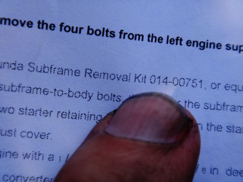 1993 Ford Taurus - A thumb partially covers a document detailing subframe removal instructions and part numbers.