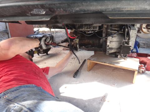 1993 Ford Taurus - Mechanic working on the underside of a vehicle, focusing on the transmission.
