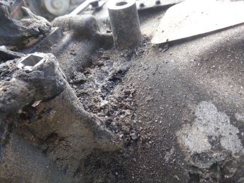 1993 Ford Taurus - A heavily soiled and damaged engine part is shown in close-up, with no discernible year or vehicle identification.