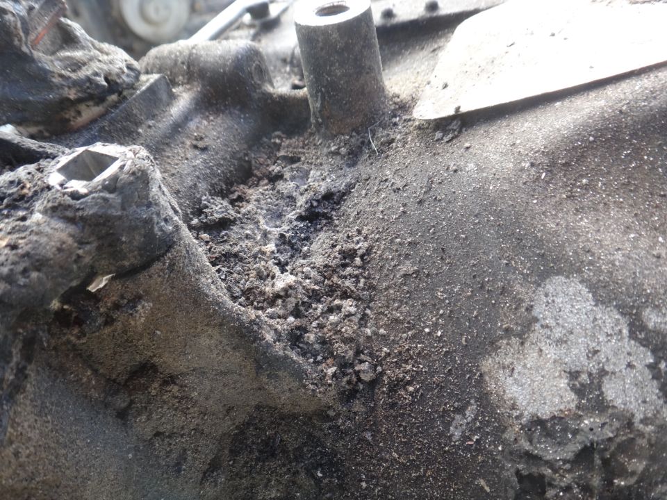 Close-up of a corroded and dirty engine component with visible debris and damage