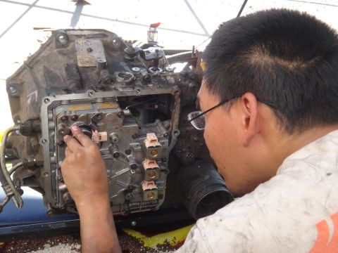 1993 Ford Taurus - A mechanic works on a disassembled transmission, focusing on the intricate internal components.