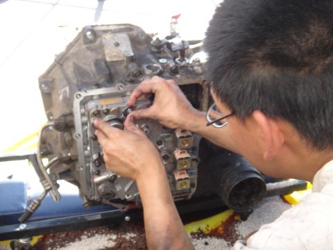 1993 Ford Taurus - A person works on a transmission valve body, which is a component of a vehicle's drivetrain.