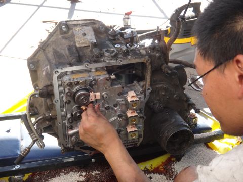 1993 Ford Taurus - A person works on a transmission valve body, adjusting a component with their hand.