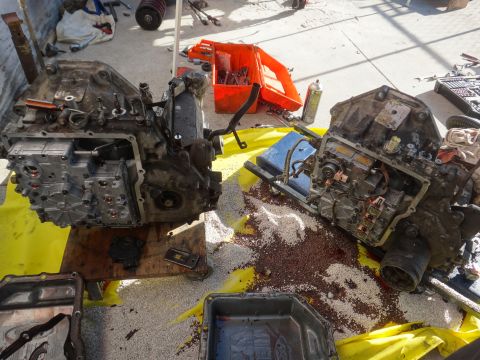 1993 Ford Taurus - Two automatic transmissions are disassembled on a yellow tarp, surrounded by tools and scattered parts.