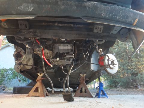1993 Ford Taurus - The underside of a vehicle is elevated on jack stands, revealing its mechanical components and suspension system.