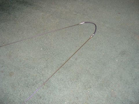 Two throttle cables, one with a black protective sleeve, laid out on a carpeted surface