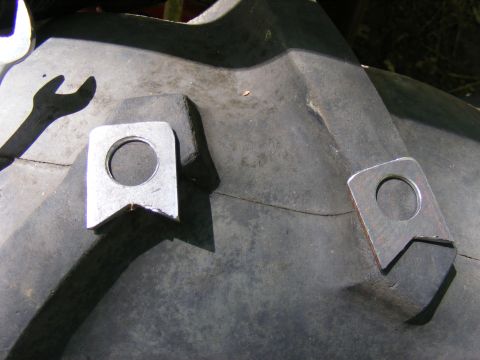 Close-up of a tire with two welded metal lugs and a wrench