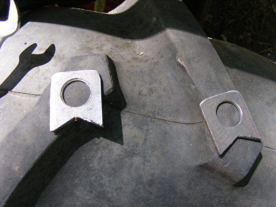 Close-up of a tire with two welded metal lugs and a wrench