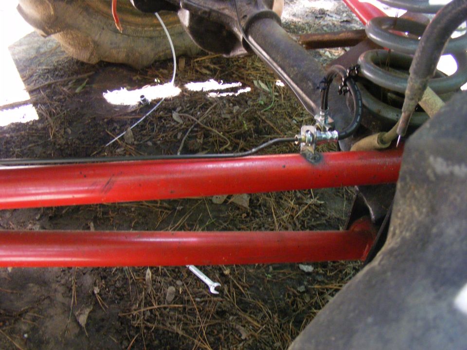 Close-up of red suspension bars, brake lines, and a tire on a vehicle