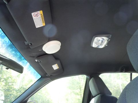2001 Ford Crown Victoria - The interior ceiling of a car shows two sun visors, a dome light, and a reading light, with a warning sticker visible.