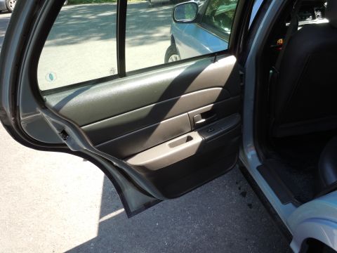 2001 Ford Crown Victoria - View of the interior door panel and rear seat of a gray sedan, with another vehicle partially visible outside.