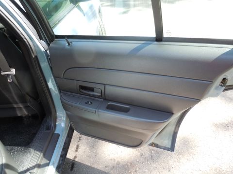 2001 Ford Crown Victoria - The interior door panel of a vehicle, showing the door handle, window controls, and a portion of the seat.