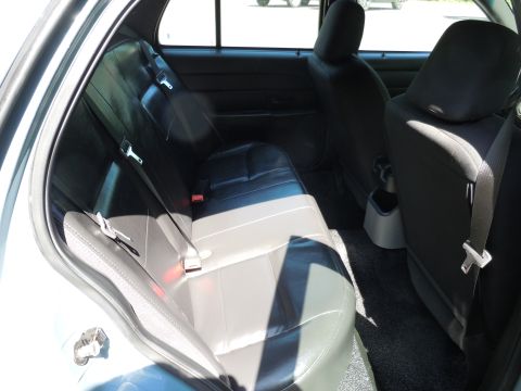 2001 Ford Crown Victoria - The rear interior of a car shows black leather seats and seatbelts.
