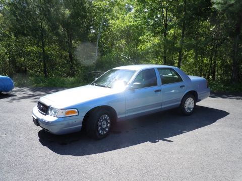 2001 Ford Crown Victoria - A light blue 2001 Ford Crown Victoria sedan is parked outdoors on an asphalt surface.