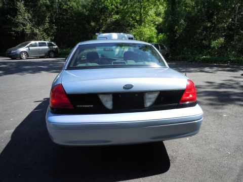 2001 Ford Crown Victoria - The rear of a light blue 2001 Ford Crown Victoria is visible, parked outdoors with another vehicle in the background.