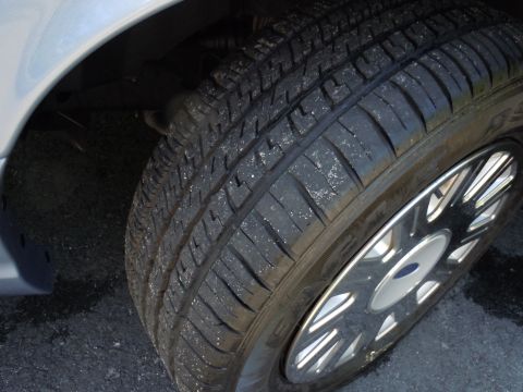 2001 Ford Crown Victoria - A close-up view of the front passenger-side wheel and tire assembly of a Ford Crown Victoria.