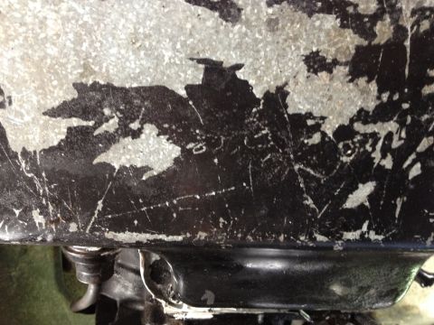 1988 Ford Bronco - Close-up of a worn metal surface showing peeling paint and scratches.