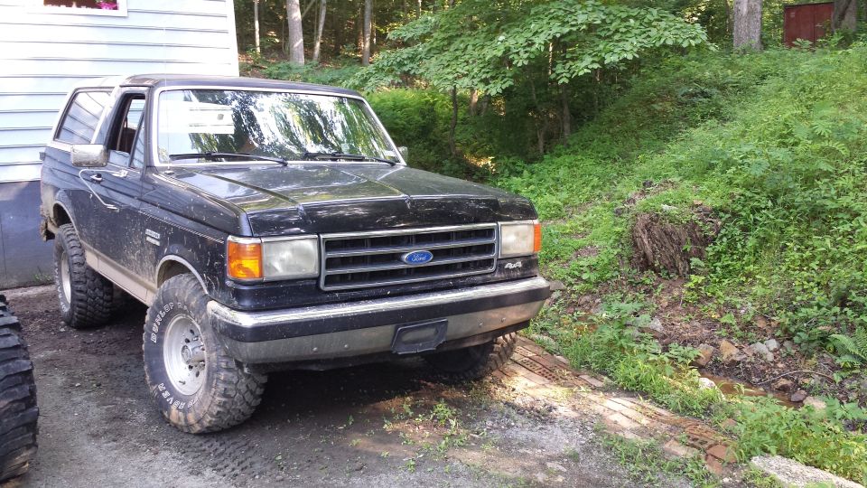 Black Ford Bronco with off-road tires parked next to a building