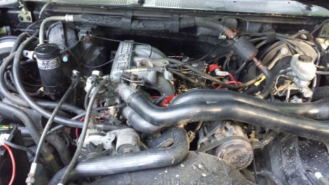 1991 Ford Bronco - Close-up view of a V8 engine bay, showing various hoses, the intake manifold, and other engine components.