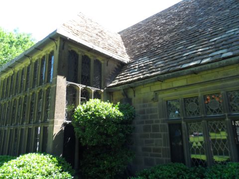 1971 Ford Ranchero - A large stone building with many windows and a textured roof is seen from a low angle, partially obscured by bushes.